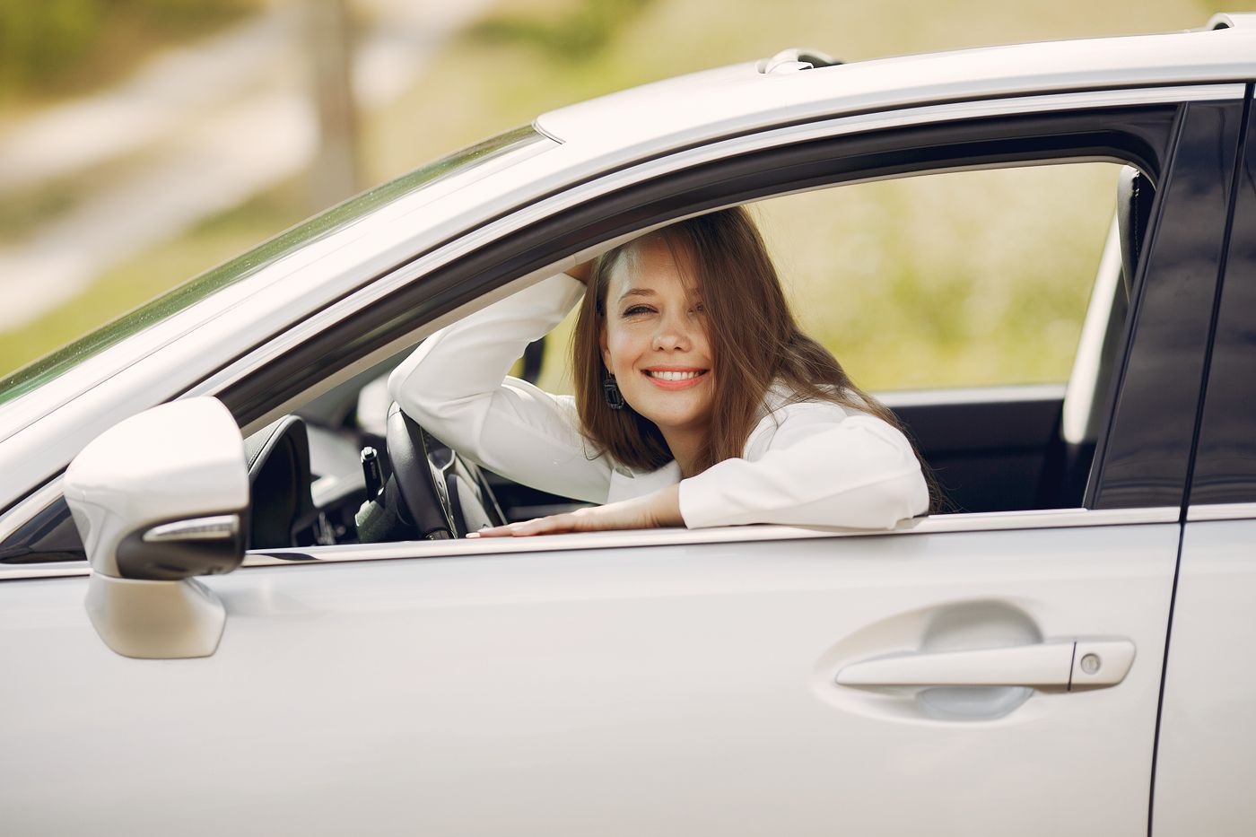 Condutora sorridente ao volante do seu carro, durante o dia
