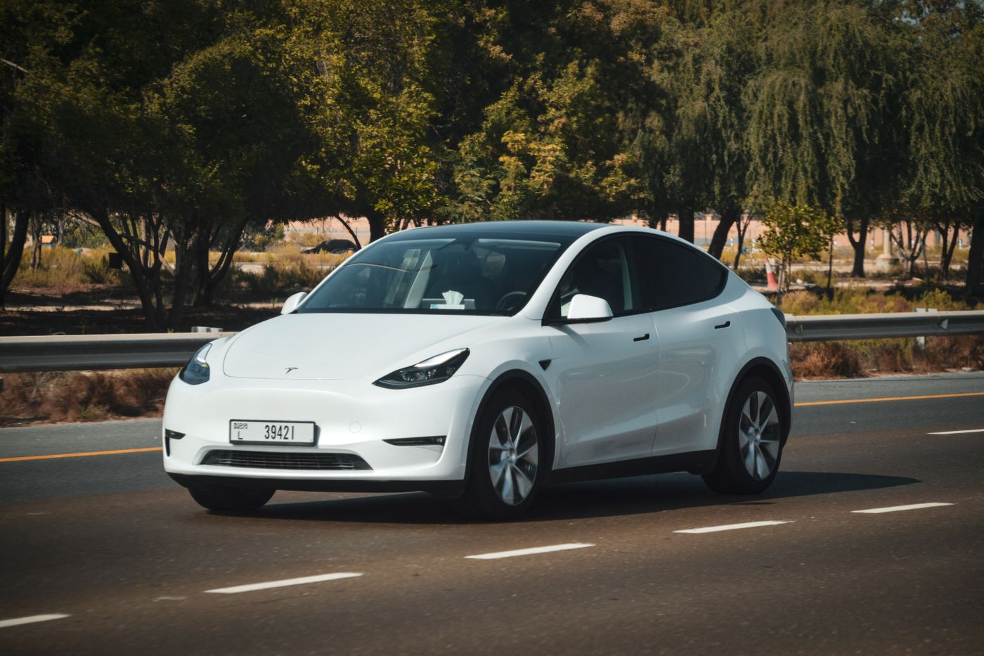 Tesla branco a conduzir numa estrada, durante o dia